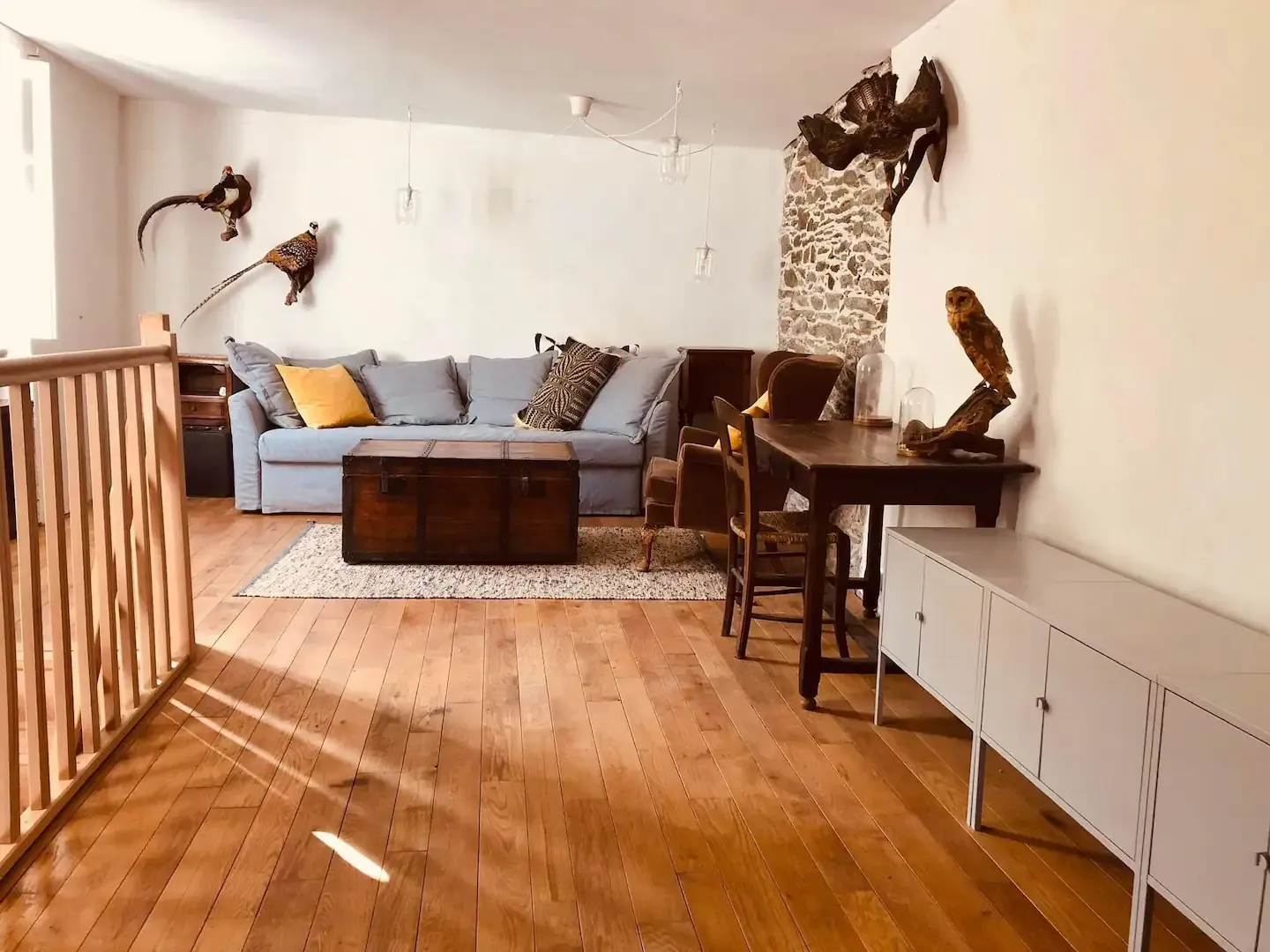 Le salon baigné de lumière, canapé bleu et plancher en chêne