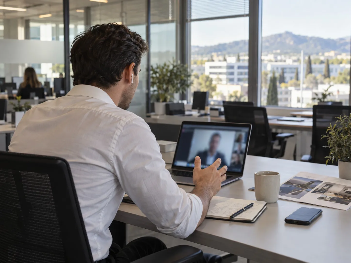 Un commercial en appel vidéo avec un client, vu de dos, dans un bureau lumineux