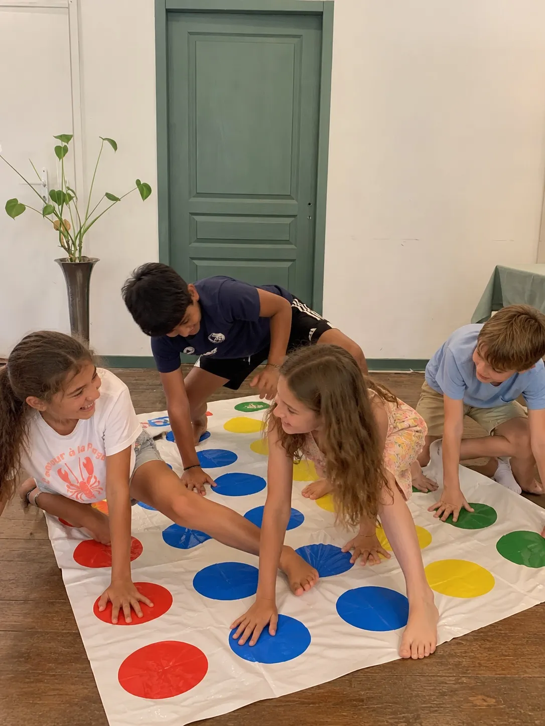 Quatre enfants qui rient en jouant au Twister dans la salle
